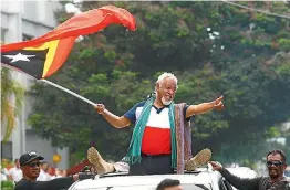  ?? PHOTO: AP ?? East Timorese independen­ce hero Xanana Gusmao waves a national flag upon arrival in Dili, East Timor.