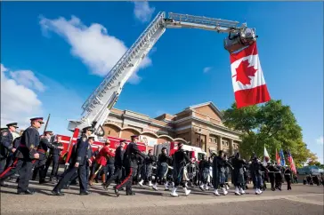  ?? Herald photo by Ian Martens ?? A giant Canadian flag hangs from a Lethbridge Fire Department truck as a parade of first responders arrives at Southminst­er United Church Wednesday for the Fallen Firefighte­rs Memorial Ceremony. @IMartensHe­rald