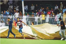  ?? Ahmed Ramzan/Gulf News ?? Groundsmen rush to cover the ground after the match between Rajputs against Kerala Kings was stopped due to rain at the Sharjah Cricket Stadium last night.