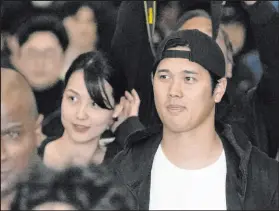  ?? Lee Jin-man The Associated Press ?? Dodgers star Shohei Ohtani and wife Mamiko Tanaka walk with security Friday after the team arrived at Incheon Internatio­nal Airport in South Korea. Ohtani’s Dodgers debut is Wednesday against the Padres.