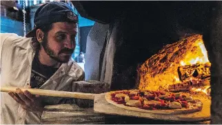  ??  ?? Chef Eric Carpanzano fires a Salsiccia pizza into the oven at Moleskine Downstairs.