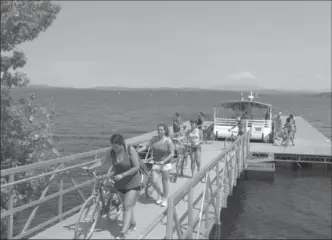  ?? WILSON RING, THE ASSOCIATED PRESS ?? Bicyclists walk their bikes after getting off a special ferry across a cut in an abandoned railroad causeway from the Vermont mainland to the Lake Champlain islands.