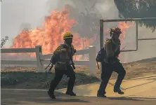  ?? David McNew / Getty Images ?? Firefighte­rs react to flames at the Blue Ridge Fire in Yorba Linda ( Orange County). That blaze has engulfed 8,000 acres.