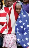  ?? Associated Press ?? In this Sept. 1, 2005, file photo, Milvertha Hendricks, 84, covered with a blanket depicting a U.S. flag, waits in the rain with other flood victims outside the convention center in New Orleans. When taking the photo, photograph­er Eric Gay recalls,...