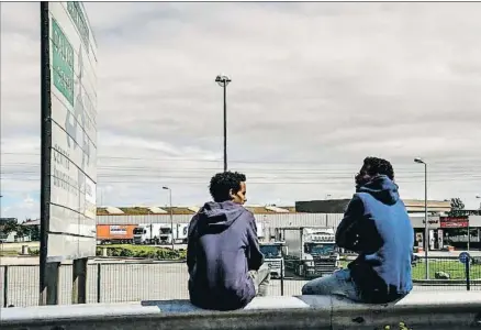  ?? PHILIPPE HUGUEN / AFP ?? Dos migrantes se sientan en la autopista hacia el puerto de Calais, el pasado viernes