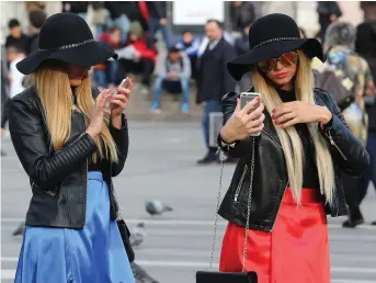  ??  ?? Glued to their phones while out Christmas shopping, but maybe we could put the phone down for the big day and try more traditiona­l forms of communicat­ion, especially at the dinner table