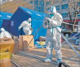 ?? BLOOMBERG ?? Workers in protective gear dismantle a temporary shelter outside a neighbourh­ood placed under lockdown due to Covid in Beijing.