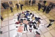  ?? SCOTT KEELER/THE TAMPA BAY TIMES ?? About 20 protesters participat­e in a ‘die-in’ on the fourth floor rotunda of the Florida Capitol in Tallahasse­e Tuesday as they continue to push for an assault weapons ban.