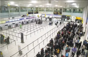  ?? Gareth Fuller / Press Associatio­n ?? Passengers line up at Gatwick as the airport works to clear a backlog of flights delayed by drone incursions that began Wednesday evening. A married couple have been arrested.