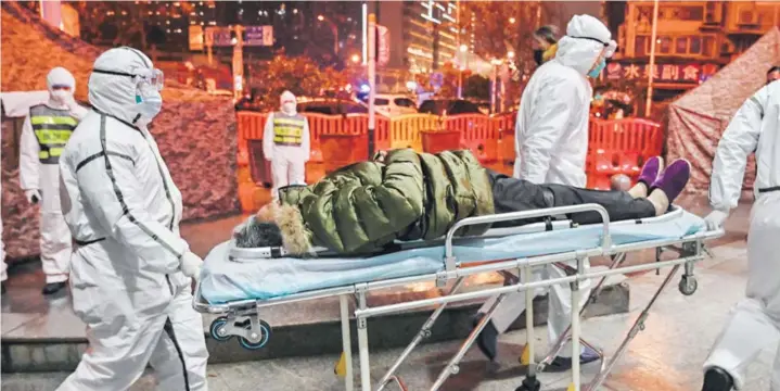  ??  ?? ► Miembros del personal médico con vestimenta de protección llegan con un paciente al hospital Wuhan Red Cross, en Wuhan, China, el 25 de enero.