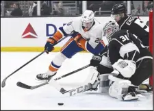  ?? Associated Press ?? New York Islanders right wing Hudson Fasching (20) shoots a wraparound shot as Los Angeles Kings goaltender David Rittich (31) and defenseman Andreas Englund (5) defend during the first period on Monday in Los Angeles. The Kings won 3-0.