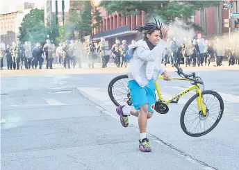  ?? — AFP photo ?? A protester grabs his bike as the police use tear gas and rubber bullets to disperse the crowd gathered near the White House as demonstrat­ions against George Floyd’s death continue.