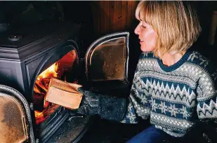  ??  ?? In the line of fire: Topping up the logs in a wood burner on a chilly night