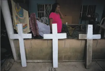  ?? Rebecca Blackwell / Associated Press ?? Isabel Osorio Luna looks at crosses being painted in Coatzacoal­cos, Mexico, on July 1 for the graves of her great-grandchild­ren. They and their parents were killed by cartel members.