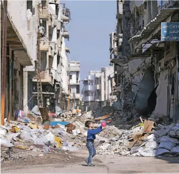  ?? FOTO: DPA ?? Ein syrischer Junge spielt in den zerbombten Überresten von Homs mit einem Ball.