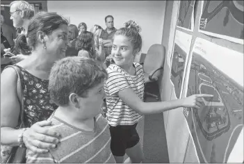  ?? MITCH MACDONALD/ ?? Stratford’s Donna MacLeod, from left, and her children, Malcolm and Maggie Power, look over some concept designs of the town’s “community campus vision” following a public meeting Wednesday night. While the idea is in the preliminar­y stages, Stratford Mayor David Dunphy said a limited amount of available land in the town means a parcel for the project would have to be secured relatively soon.