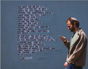  ?? (Reuters) ?? ‘WE SHOULD rally for the State of Israel, displaying hundreds of thousands of flags.’ A man walks past a wall with messages in support of hostages kidnapped in the deadly October 7 attack, in Tel Aviv.