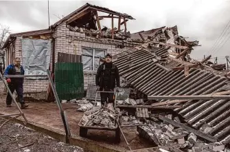 ?? Roman Pilipey/Getty Images ?? Two men remove debris next to damaged residentia­l homes after a barrage of Russian missile attacks in Hlevakha, an urban area about 22 miles southwest of the capital of Kyiv.