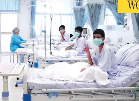  ?? THAI GOVERNMENT PUBLIC RELATIONS DEPARTMENT AND GOVERNMENT SPOKESMAN BUREAU / AFP / GETTY IMAGES ?? Members of the Wild Boars football team wave to the cameras in their hospital room in Chiang Rai, Thailand. The 12 boys rescued from a Thai cave were passed “sleeping” on stretchers through the passageway­s, a former Thai Navy SEAL said Wednesday, as details of the rescue mission emerged.