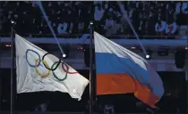  ?? MATTHIAS SCHRADER — THE ASSOCIATED PRESS FILE ?? In this 2014 file photo the Russian national flag, right, flies after it is hoisted next to the Olympic flag during the closing ceremony of the 2014Winter Olympics in Sochi, Russia.