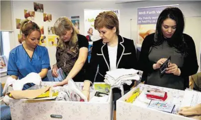  ??  ?? BOXING CLEVER: First Minister Nicola Sturgeon looks at the contents of a Baby Box for parents of newborns