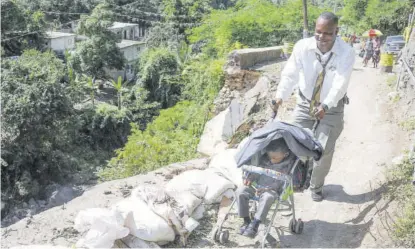  ??  ?? Karim Mchorgh pushes his toddler, Karim Jr across the most treacherou­s section of Gordon Town Road on Sunday.