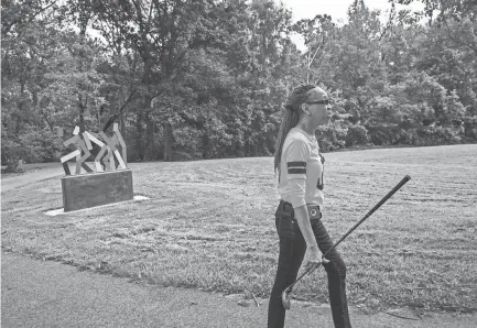  ?? YALONDA M. JAMES/THE COMMERCIAL APPEAL ?? Debra Lovelace, president of the Denver Park Neighborho­od Associatio­n, walks with a golf club on Aug. 23 during a visit to Denver Park, located in Frayser.