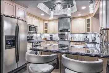  ??  ?? The kitchen has clean, white cabinets with black, granite tops.