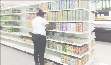  ??  ?? Packing in process: A Foodmaxx employee diligently packing a shelf in the supermarke­t ahead of its opening tomorrow