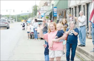  ?? ANDY SHUPE NWA DEMOCRAT-GAZETTE ?? Angie Huff of Prairie Grove, holding her grandson Baker Redfearn, cheers and waves during a parade in downtown Prairie Grove to welcome home Tyler Franks, an officer with the Prairie Grove Police Department who was shot May 4 while responding to a domestic disturbanc­e. Downtown streets were lined with residents holding signs, flags and other blue parapherna­lia for the celebratio­n.