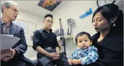  ?? STEVE BOSCH/ PNG ?? Dr. Neil Pollock, left, chats with the Yu family — dad Flynn, mom Flora and baby Clark — about a new method of circumcisi­on in his examinatio­n room.