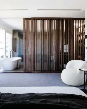  ??  ?? MAIN BEDROOM SUITE This page and opposite Sliding slatted-timber screens are used to define the zones, delivering separation and privacy without impeding light. Molteni&C ‘Wish’ bed. Saarinen ‘Tulip’ side tables, Dedece. MDF Italia ‘K’ table, Hub Furniture. Joy armchair, Jardan. Artwork by George Byrne. Walls painted Dulux Christobel. >