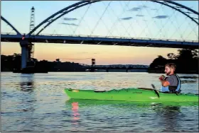  ??  ?? in the distance and the Broadway Bridge nearby, Samuel Ellis, owner of Rock Town River Outfitters, leads a paddling tour of the Arkansas River.
With the Baring Cross Bridge