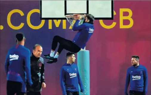  ??  ?? Gerard Piqué se cuelga del aro de la canasta que hay en el campo de entrenamie­nto del Barcelona en la sesión de ayer.