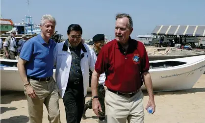  ??  ?? George HW Bush, right, walks with his fellow former president Bill Clinton and the Thai foreign minister in February 2005 as they survey damage from the Indian Ocean tsunami. Photograph: Saeed Khan/AFP/Getty Images