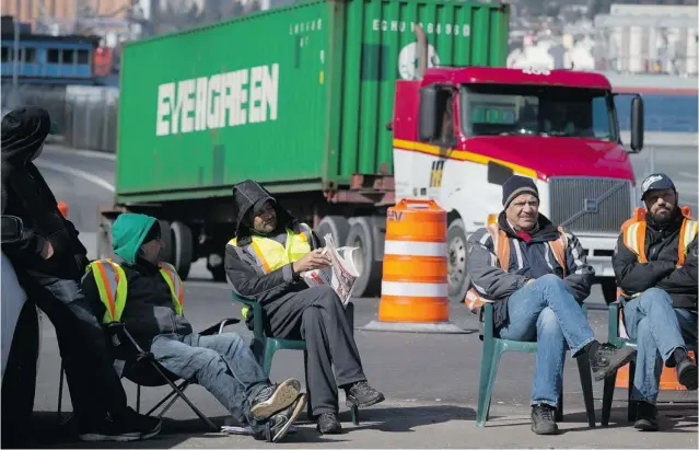  ?? DARRYL DYCK/ THE CANADIAN PRESS ?? Striking container truck drivers sit at a picket line as a truck leaves Port Metro Vancouver earlier this week. Their leadership and the government were meeting late Friday to discuss the 14- point proposal that was presented to the drivers late...