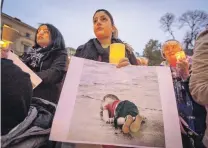  ?? PHOTO: GETTY IMAGES ?? Powerful image . . . A woman holds a picture during a vigil in Melbourne in remembranc­e of Aylan Kurdi, an infant Syrian refugee who drowned in 2015, while also protesting the Australian Government’s refugee policy.
