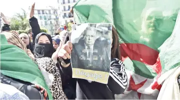  ?? — AFP photo ?? An Algerian protester holds a poster bearing a photo of Bensalah with slogan in Arabic and French: ‘Bensalah leave, we don’t trust you’ during an anti-system demonstrat­ion in the capital Algiers.