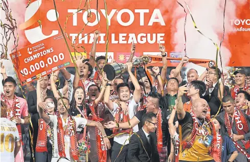  ??  ?? Chiang Rai United chief adviser Miti Tiyapairat, centre, lifts the trophy as the Beetles celebrate winning the Thai League 1 title last year.