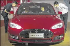  ?? MARK SCHIEFELBE­IN / AP ?? Staff members talk with visitors as they sit inside a Tesla Model S electric car at the Beijing Internatio­nal Automotive Exhibition in Beijing.