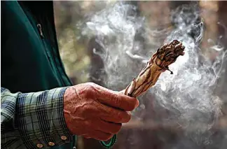  ?? MICHAEL MACOR / SAN FRANCISCO CHRONICLE VIA AP ?? Wes James smudges the area with sage smoke as members of the Native American Miwuk tribe continue their quest of rebuilding the small village of their ancestors known as Wahhoga Village, on the valley floor of Yosemite National Park as seen on Mar. 29, 2018.