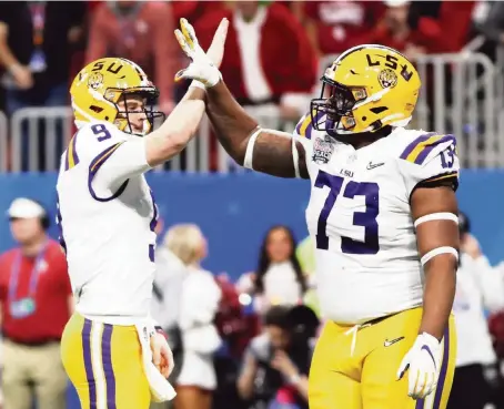  ?? GREGORY SHAMUS Getty Images ?? LSU quarterbac­k Joe Burrow, left, and offensive lineman Adrian Magee celebrate one of Burrow’s bowl-record seven TD passes in the first half.