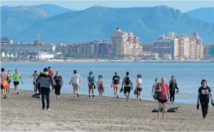  ??  ?? Varias personas pasean por la playa en Valencia.