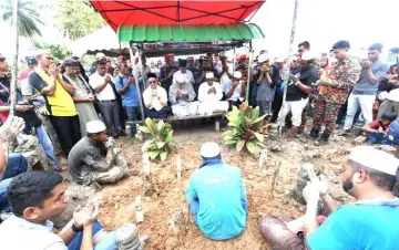  ?? — Bernama photo ?? Family members, relatives, friends and colleagues pray at the funeral of Muhammad Adib.