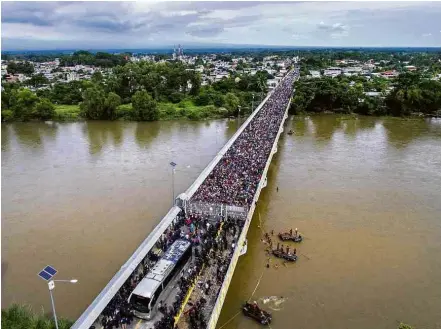  ?? Fotos Pedro Pardo/AFP ?? A caravana de migrantes é barrada por militares mexicanos na ponte que liga o país à Guatemala