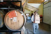  ??  ?? A customer leaves the bottle shop with boxes of beer while sour beer ferments in barrels at Hill Farmstead Brewery.