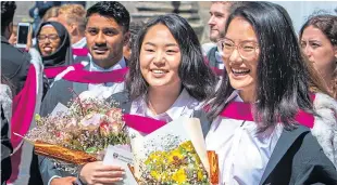  ??  ?? All smiles as the new graduates come into the quad after the ceremony.