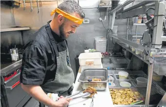  ??  ?? Noble Fry-It executive chef Jeremy Kuney makes sure the temperatur­e of his fried chicken is hot enough as he prepares to-go orders.