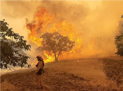  ?? Jose Luis Villegas/Sacramento Bee/TNS ?? ■ Firefighte­r Wyatt Belden from Gold Ridge Fire Protection in Sonoma County monitors a fire burning Monday off Keck Road, just west of Lakeport, Calif.