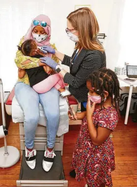  ?? Elizabeth Conley / Staff photograph­er ?? Dr. Rebecca Berens tries to get Sereen Wheeler’s temperatur­e as she sits on her mother’s lap during a checkup in Berens’ Heights office.